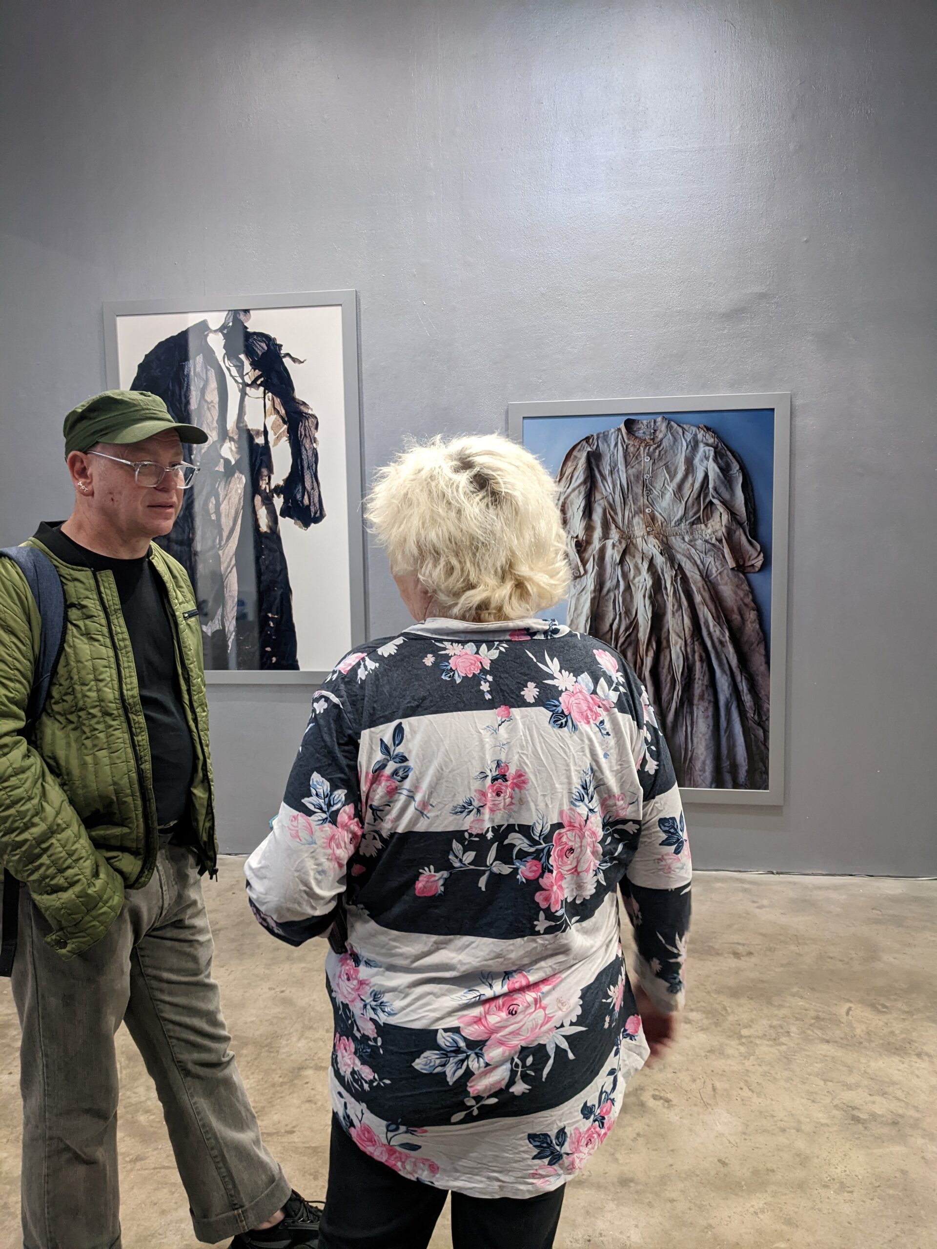 two people looking at photographs in a gallery